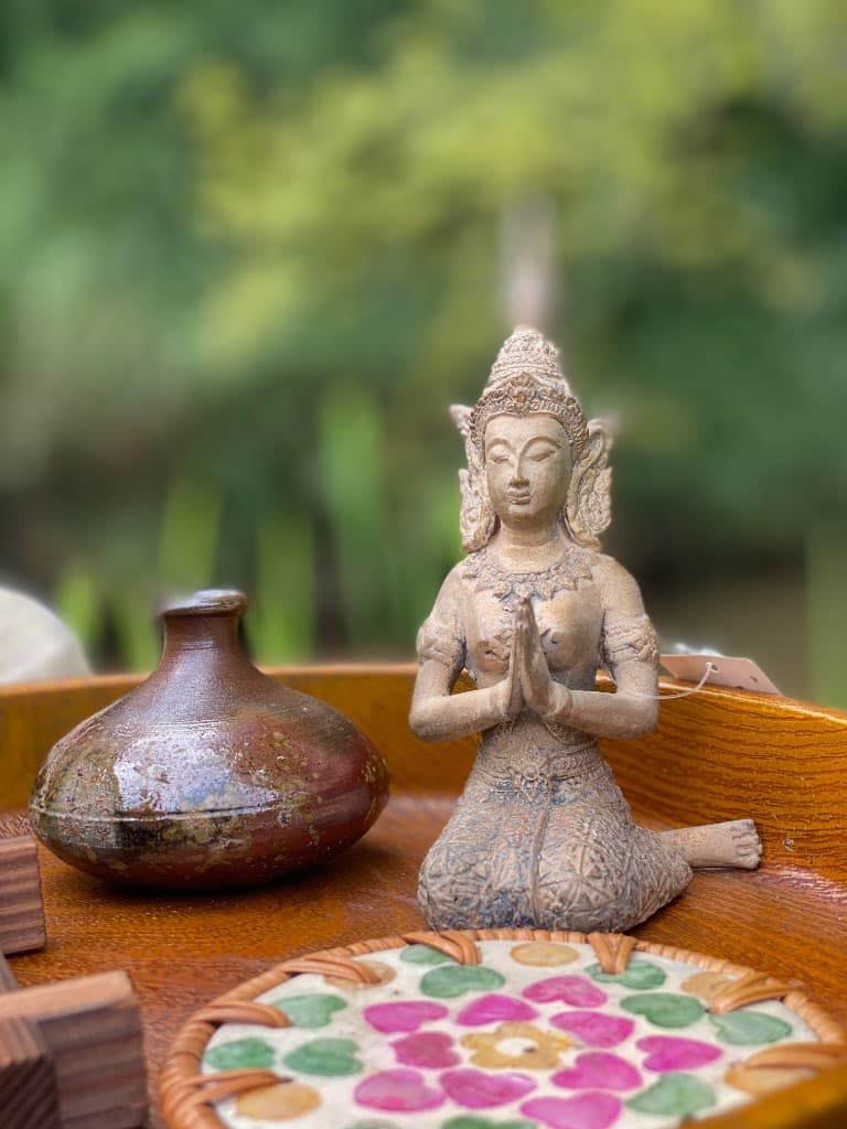 Seated figurine with a bronze bottle on a wooden tray
