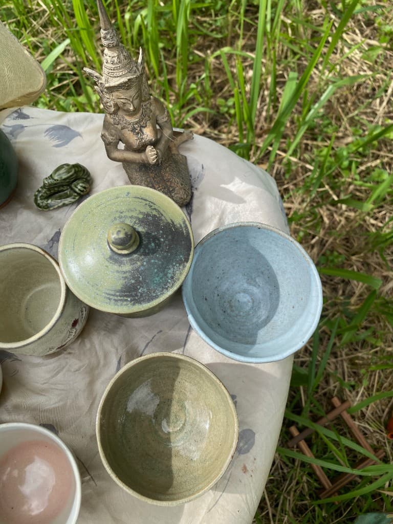 Olive lidded jar with bowls and a seated figurine in the grass