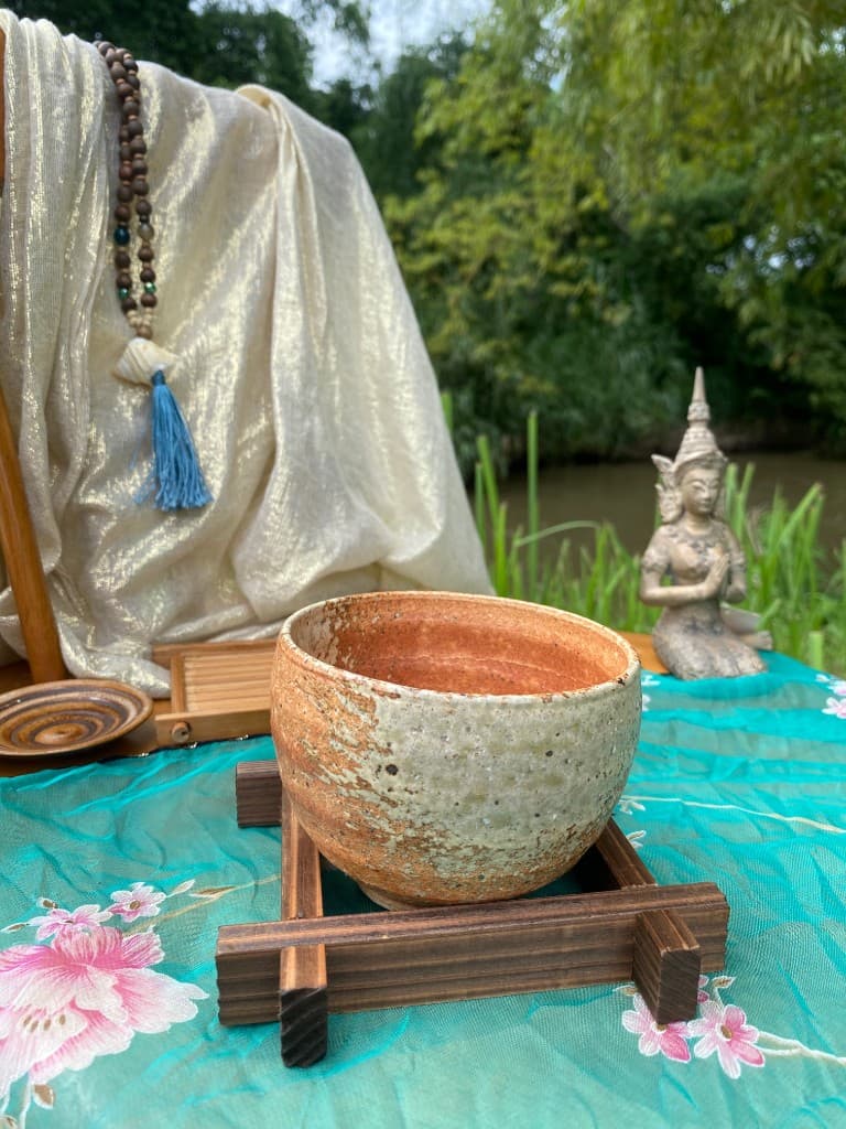 Rust-interior tea bowl on a dark wooden stand